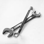 A pair of crossed metal wrenches on a clean white surface.