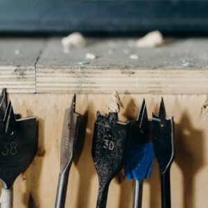 Detailed view of woodworking drill bits on a wooden surface in a workshop environment.